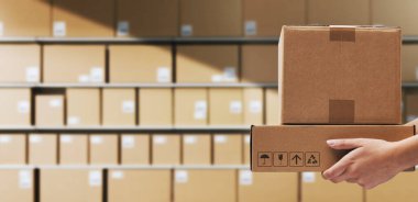 Teslimat kutuları taşıyan depo işçisi ve arka planda istiflenmiş paketler, lojistik ve sevkiyat konsepti