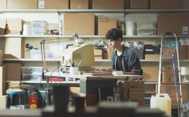 Genç inek masada oturuyor ve garajında antika bir bilgisayarla çalışıyor.