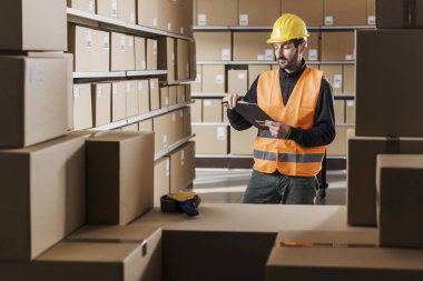 Warehouse worker holding a clipboard and checking boxes, logistics and shipment concept clipart