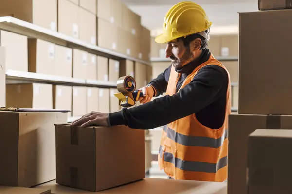 Lagerarbeiter Versiegelt Einen Karton Mit Klebeband Logistik Und Versandkonzept lizenzfreie Stockbilder