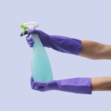 Temizlik eldiveni giyen, elinde sprey deterjan şişesi, hijyen ve temizlik konsepti tutan kadın eller.