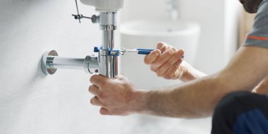 Profesyonel tesisatçı banyo lavabosunu su pompası kullanarak tamir ediyor.