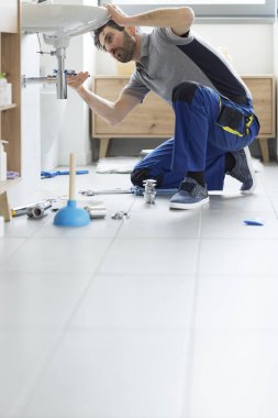 Profesyonel tesisatçı banyo lavabosunu tamir ediyor. Su pompası kullanıyor, boş kopya alanı var.