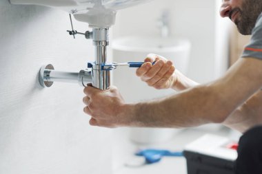 Profesyonel tesisatçı banyo lavabosunu su pompası kullanarak tamir ediyor.