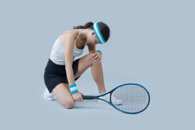 Yaralı genç bayan tenis oyuncusu, dizine, spor ve sağlık hizmetlerine dokunuyor.