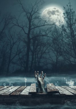 Korkunç zombi eli göldeki ahşap bir iskeleden çıkıyor. Korku ve Cadılar Bayramı konsepti.