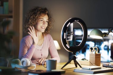 Profesyonel nüfuzlu kişi masasında oturuyor ve sosyal medya profilleri için bir video içeriği kaydediyor, bir akıllı telefon ve halka ışığı kullanıyor: sosyal medya ve iletişim konsepti