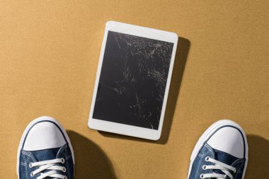 Kırık dijital tablet ve genç adam ayağı. Cihazı düşürdü. Onarıma ihtiyacı var.