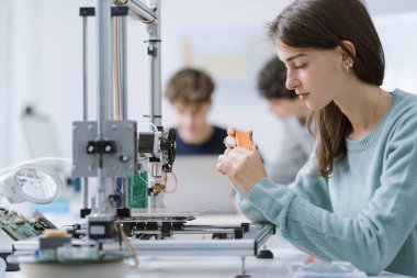 Laboratuvarda 3D yazıcı kullanan zeki kız öğrenci: eğitim, teknoloji ve bilim konsepti