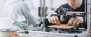 Laboratuvarda 3 boyutlu yazıcıyla çalışan zeki bir öğrenci bir prototip basıyor.