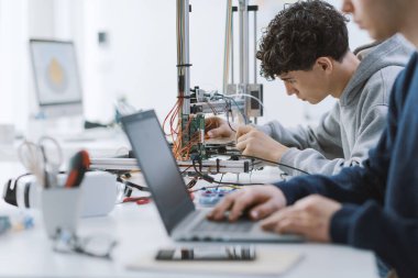 Laboratuvarda bir proje üzerinde çalışan akademik öğrenciler, bir dizüstü bilgisayar ve bir 3D yazıcı kullanıyorlar