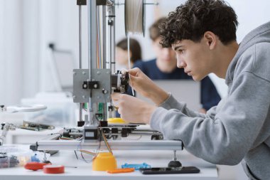 Mühendislik öğrencisi 3 boyutlu yazıcı kullanarak laboratuvarda bir prototip basıyor: eğitim, bilim ve teknoloji konsepti