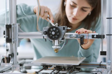 Laboratuvarda 3 boyutlu bir yazıcıyla çalışan zeki genç kız öğrenci: Eğitim ve bilim konsepti.