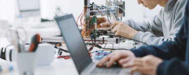 Laboratuvarda bir proje üzerinde çalışan akademik öğrenciler, bir dizüstü bilgisayar ve bir 3D yazıcı kullanıyorlar