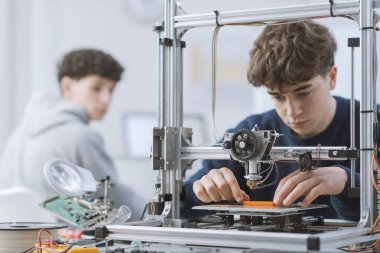 Laboratuvarda 3 boyutlu yazıcıyla çalışan zeki bir öğrenci bir prototip basıyor.