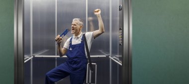 Asansörde şarkı söyleyen ve pensesini mikrofon olarak kullanan komik bir tesisatçı.