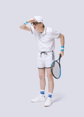 Tenis oynayan komik inek çocuk, gözünü kaçırıyor ve beyaz arka planda izole edilmiş topu göremiyor.