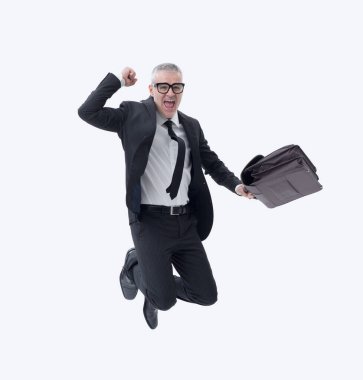 Elinde evrak çantası olan koyu renk takım elbiseli bir işadamı başarısını kutlarken sevinçle atlıyor..