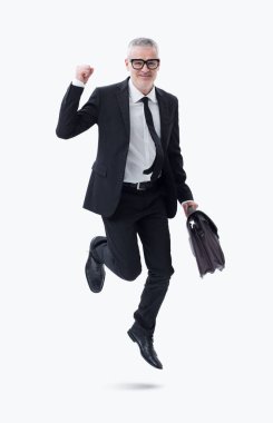 Elinde evrak çantası olan koyu renk takım elbiseli bir işadamı başarısını kutlarken sevinçle atlıyor..