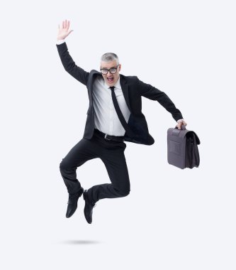 Elinde evrak çantası olan koyu renk takım elbiseli bir işadamı başarısını kutlarken sevinçle atlıyor..