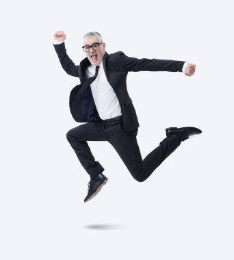 Koyu takım elbiseli bir işadamı başarısını kutlarken sevinçle atlıyor..