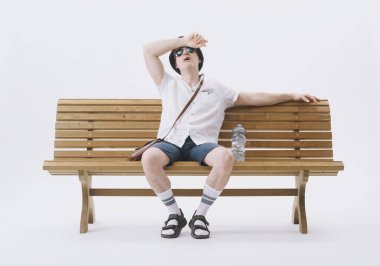 Bir bankta oturan orta yaşlı erkek turist sıcaktan muzdarip. Küresel ısınma kavramı.