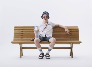 Bir bankta oturan orta yaşlı erkek turist sıcaktan muzdarip. İklim değişikliği kavramı.