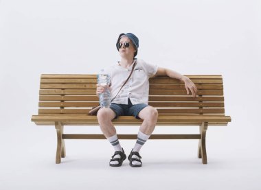 Bir bankta oturan orta yaşlı erkek turist sıcaktan muzdarip. Küresel ısınma kavramı.