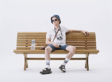 Bir bankta oturan orta yaşlı erkek turist sıcaktan muzdarip. Küresel ısınma kavramı.