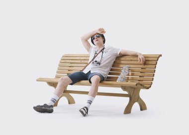 Bir bankta oturan orta yaşlı erkek turist sıcaktan muzdarip. Küresel ısınma kavramı.