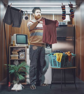 Tek odalı küçük bir stüdyo dairede tek başına yaşayan ve çamaşırları yıkayan genç adam çamaşırlarını çamaşır ipine asıyor.