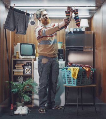 Tek odalı küçük bir stüdyo dairede tek başına yaşayan ve çamaşırları yıkayan genç adam çamaşırlarını çamaşır ipine asıyor.