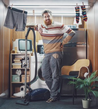 Verimli bağımsız adam tek odalı stüdyo dairesini temizliyor, yerleri süpürüyor.