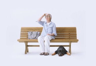 Yaşlı kadın bankta oturuyor, sıcaktan acı çekiyor. Küresel ısınma kavramı.