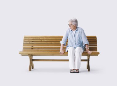 Bankta oturan yaşlı bir kadın yanındaki boşluğa bakıyor, yalnızlığı ve kederi simgeliyor..