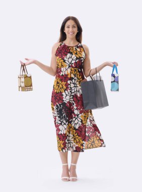 Güzel, gülümseyen genç bir kadın bir sürü alışveriş çantasıyla poz veriyor, beyaz arka planda duruyor..