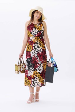 Güzel, gülümseyen genç bir kadın bir sürü alışveriş çantasıyla poz veriyor, beyaz arka planda duruyor..