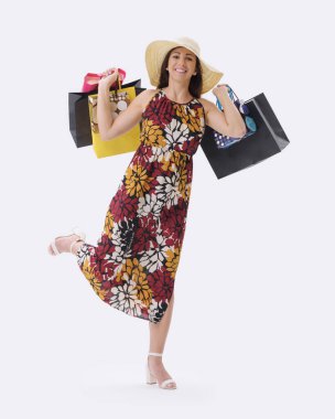 Güzel, gülümseyen genç bir kadın bir sürü alışveriş çantasıyla poz veriyor, beyaz arka planda duruyor..