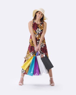 Güzel, gülümseyen genç bir kadın bir sürü alışveriş çantasıyla poz veriyor, beyaz arka planda duruyor..