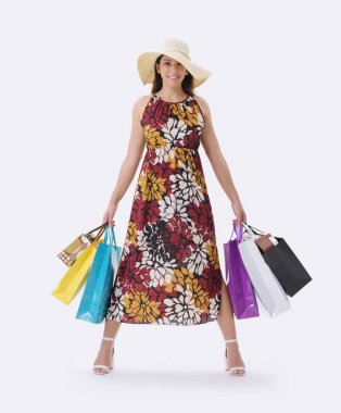 Güzel, gülümseyen genç bir kadın bir sürü alışveriş çantasıyla poz veriyor, beyaz arka planda duruyor..