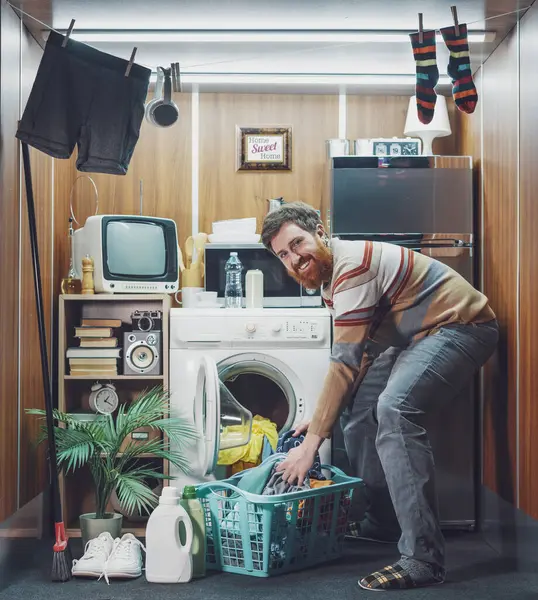 Tek odalı küçük bir stüdyo dairede tek başına yaşayan ve çamaşırları yıkayan genç adam çamaşırlarını çamaşır ipine asıyor.