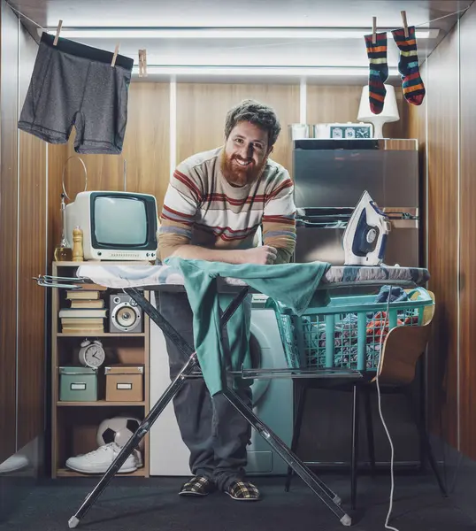 Küçük bir dairede tek başına yaşayan bağımsız bir adam. Giysileri ütülüyor ve kameraya gülümsüyor.