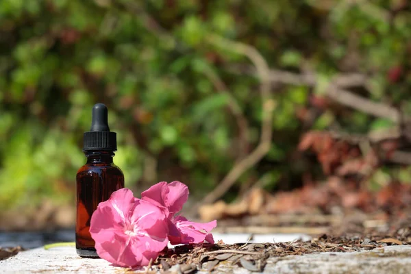 Natural remedies, aromatherapy, amber bottle. Free product space, mock-up. Pink flower, bach therapy.
