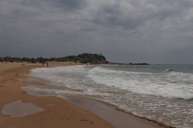 Wide sandy beach, shoreline. Cloudy sky, cloudscape.