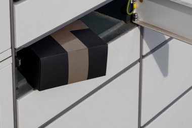 Black parcel inserted into parcel machine, concept linked to e-commerce business.