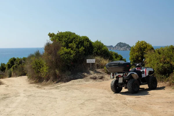 A quad parked above a picturesque beach, cliffside. Motorbike in a natural environment, no people.