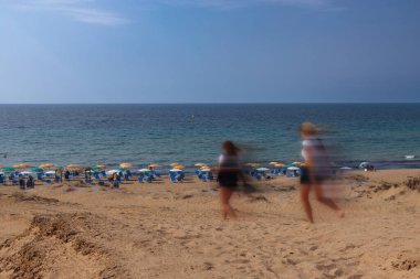 Sahilde yürüyen turistler hareket halinde, Korfu adasında kumlu plajlarda yakalandılar.