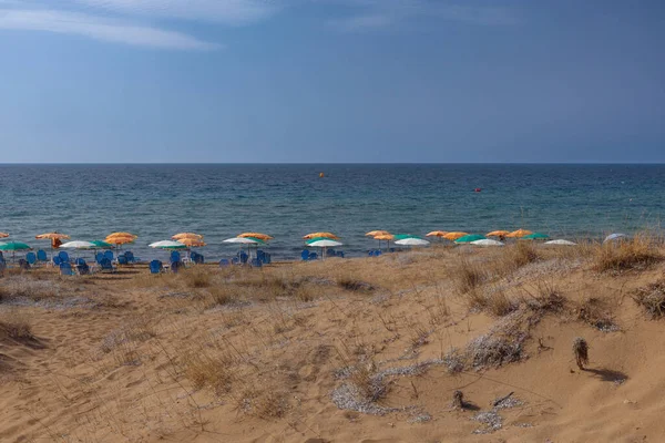 Yunanistan 'ın Korfu adasının kuzey kısmında kumlu bir plaj var. Şemsiyeler ve sandalyeler sahilde.