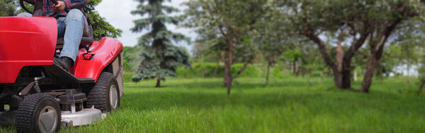 Mower at work on vibrant grass. Copy space banner.
