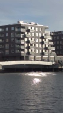 Güneş ışığını yansıtan suyun yanındaki çağdaş apartman dairesi.